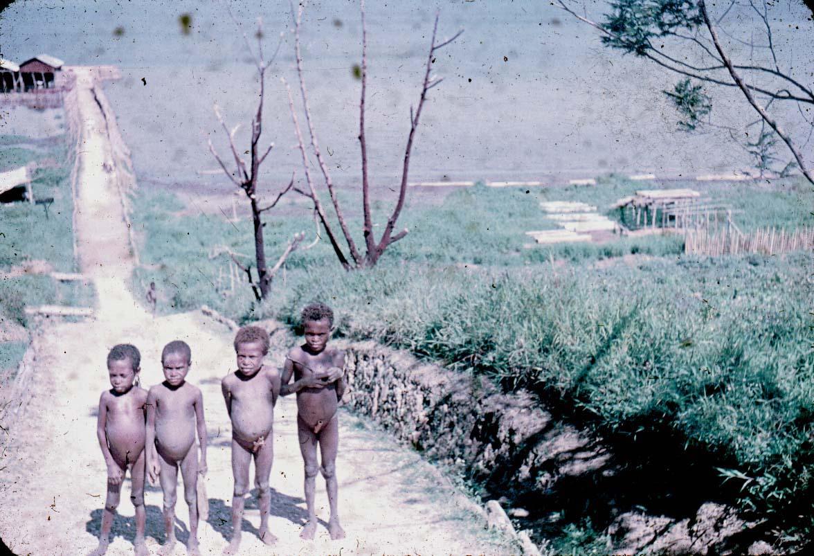 BD/24/11 - 
Afbeelding met op de achtergrond een aanlegsteiger voor Beavers; op de voorgrond vier Papuakinderen.
