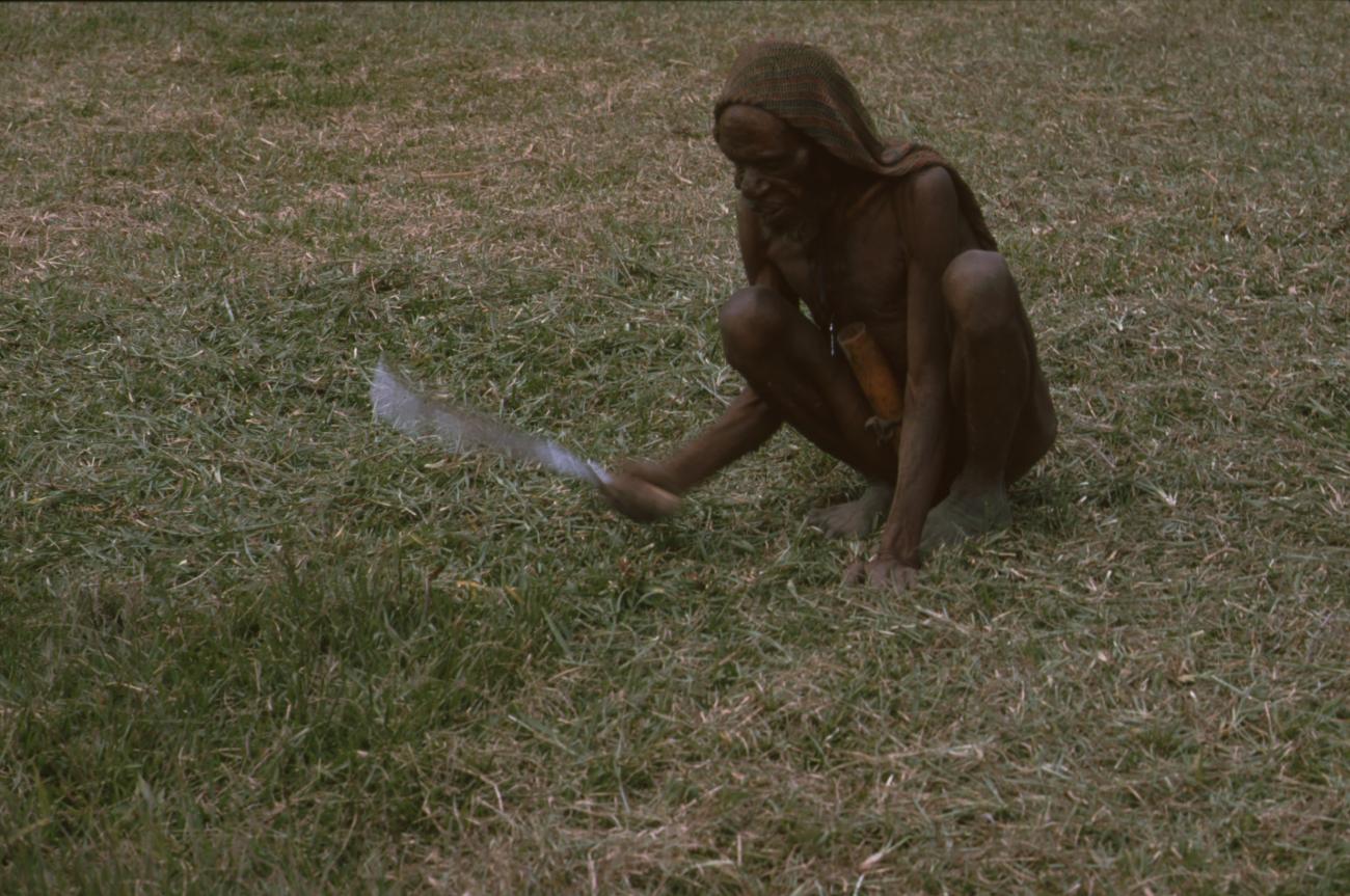 BD/166/377 - 
Papua man is cutting his grass in a squating position
