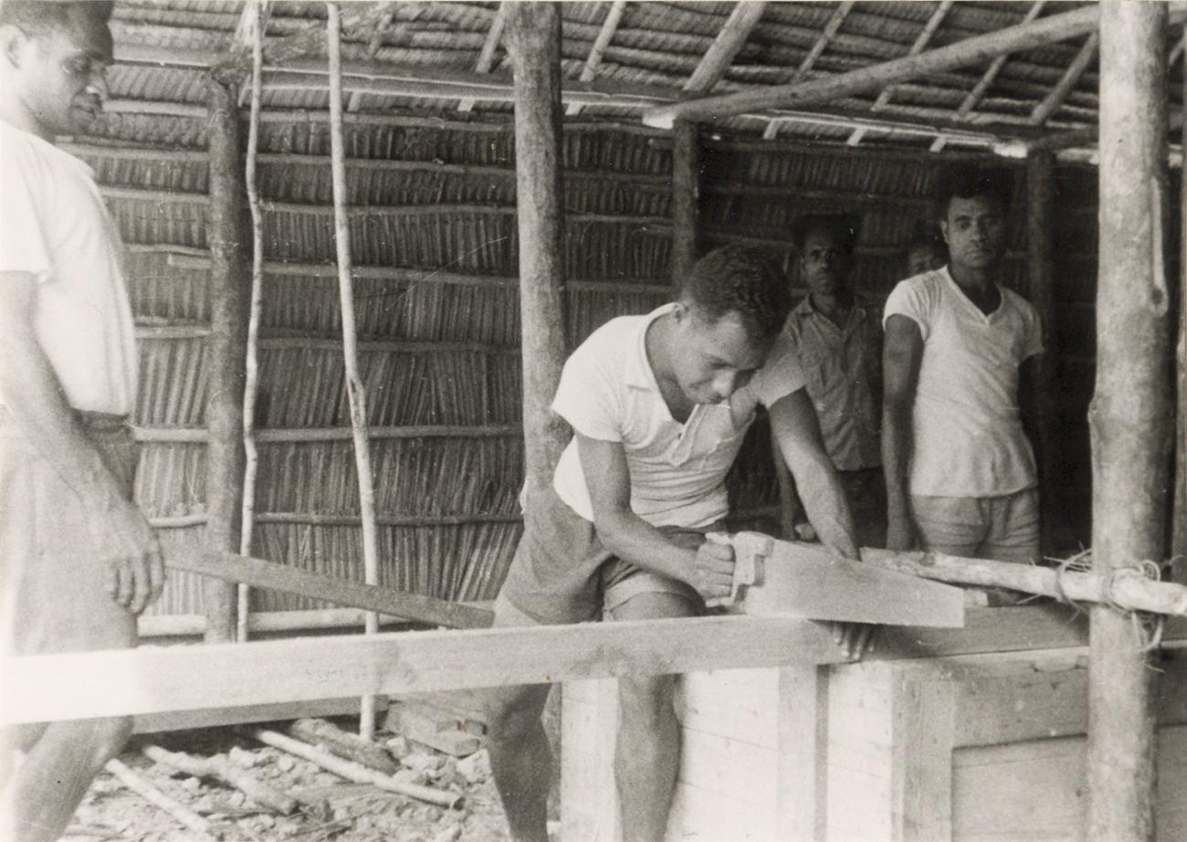 BD/309/62 - 
Dorp Teminabuan, mannen bezig met houtbewerking
