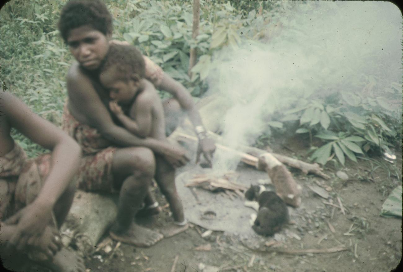 BD/144/54 - 
Papoea-vrouwen bij vuurtje, waarvan een met kind
