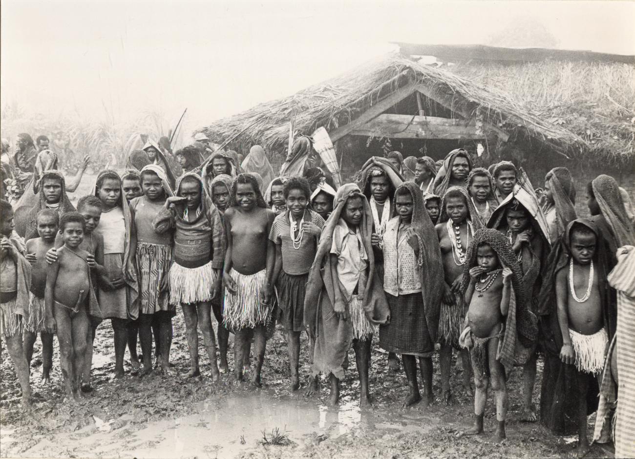 BD/326/31 - 
Groep kinderen en vrouwen in de regen verzameld voor een schooltje in de Kamu-vallei
