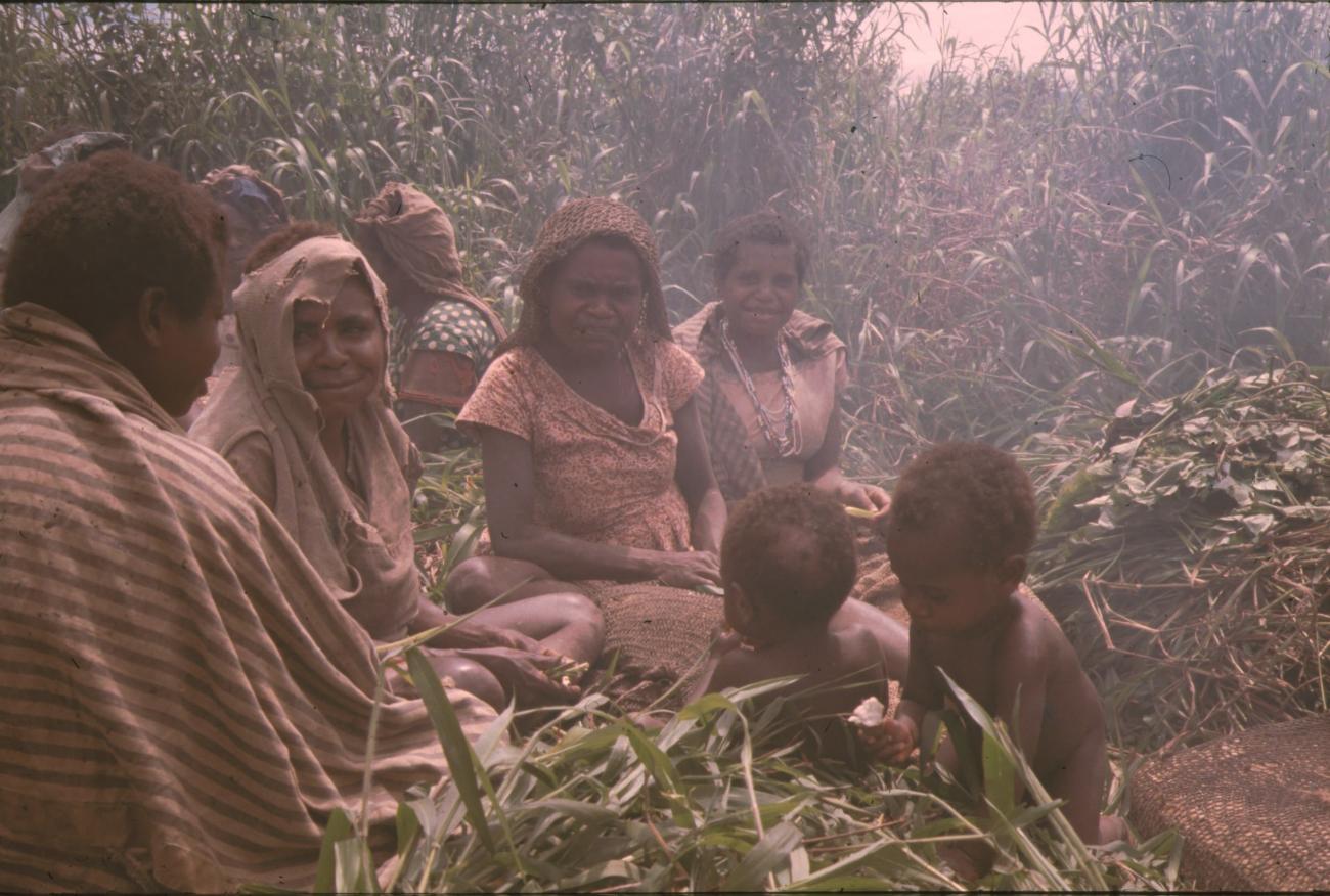BD/132/112 - 
groepje zittende vrouwen en kinderen in de rook
