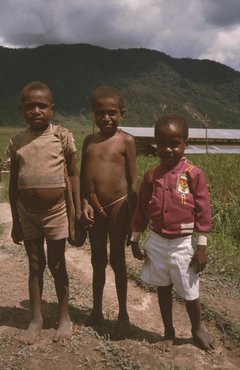 BD/132/142 - 
groepsfoto van drie jongens, waarvan een een peniskoker draagt
