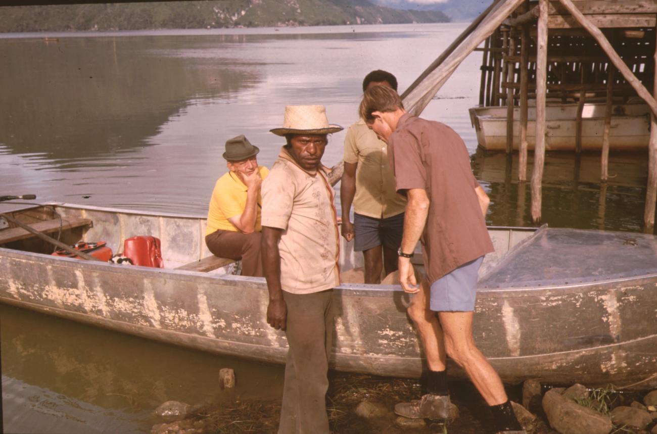 BD/132/150 - 
twee Papuanen en twee Westerlingen in en naast een motorboot
