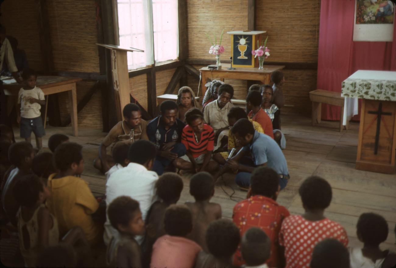 BD/132/2 - 
groepsfoto mensen  in kerk die luisteren naar man met microfoon
