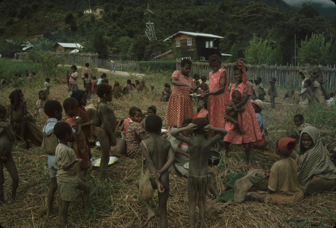 BD/132/7 - 
voedselbereiding door vrouwen en kinderen op het gras
