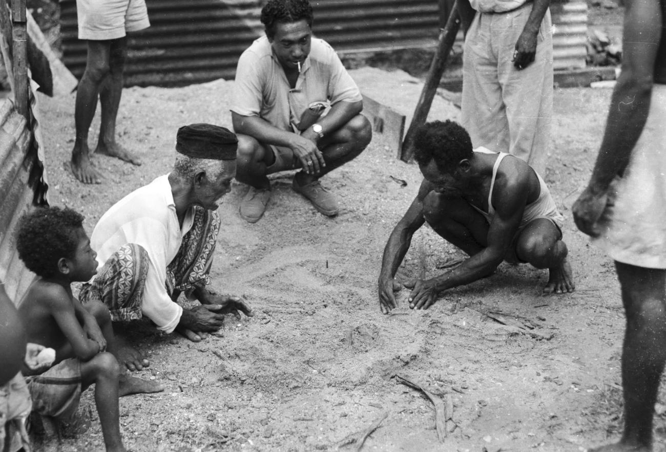 BD/133/1181 - 
Papoea-mannen tekenen een kaart in het zand
