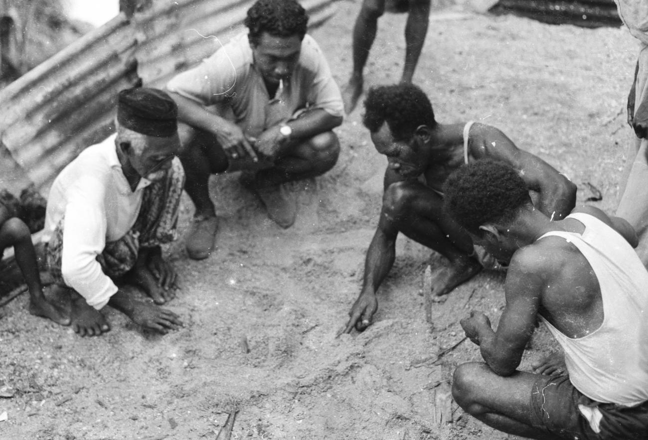 BD/133/1182 - 
Papoea-mannen tekenen een kaart in het zand

