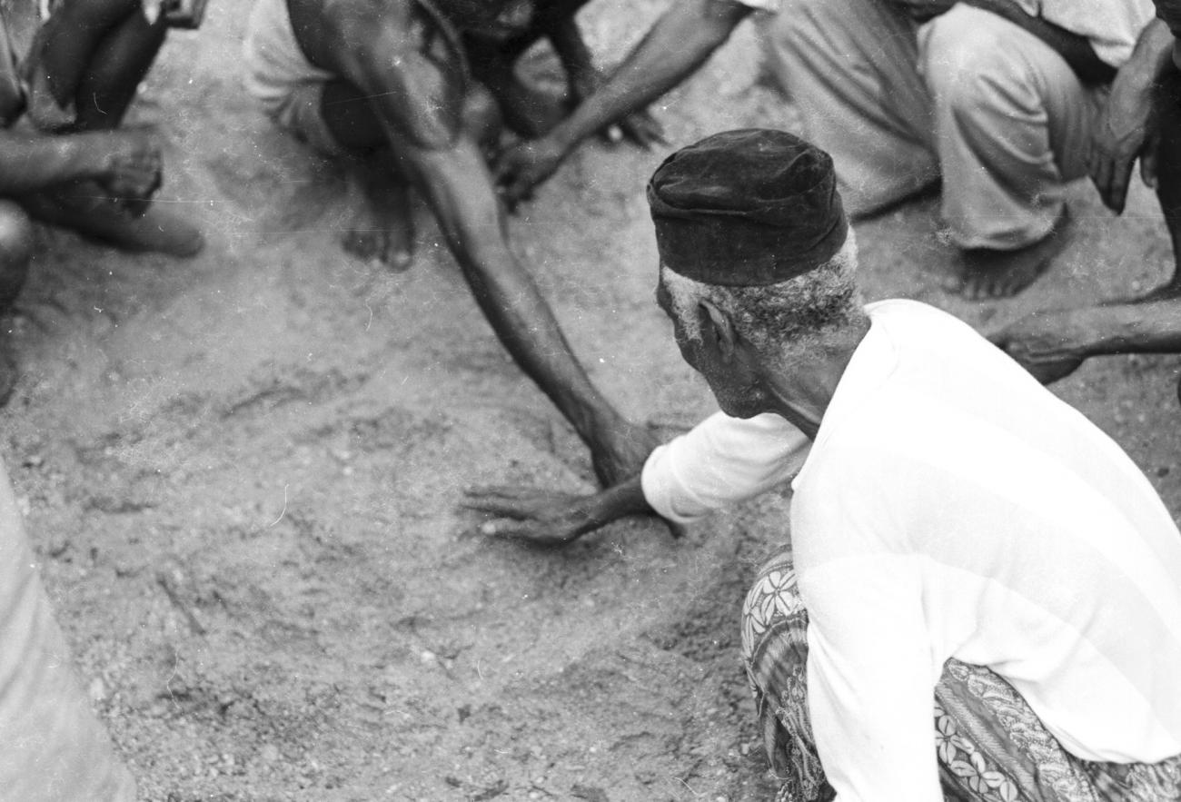 BD/133/1183 - 
Papoea-mannen tekenen een kaart in het zand
