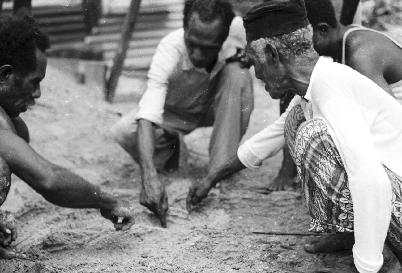 BD/133/1184 - 
Papoea-mannen tekenen een kaart in het zand
