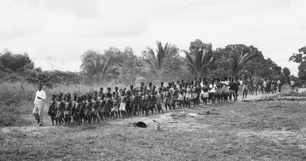 BD/133/179 - 
Een grote groep Papoea&#039;s (muziek????) onderweg
