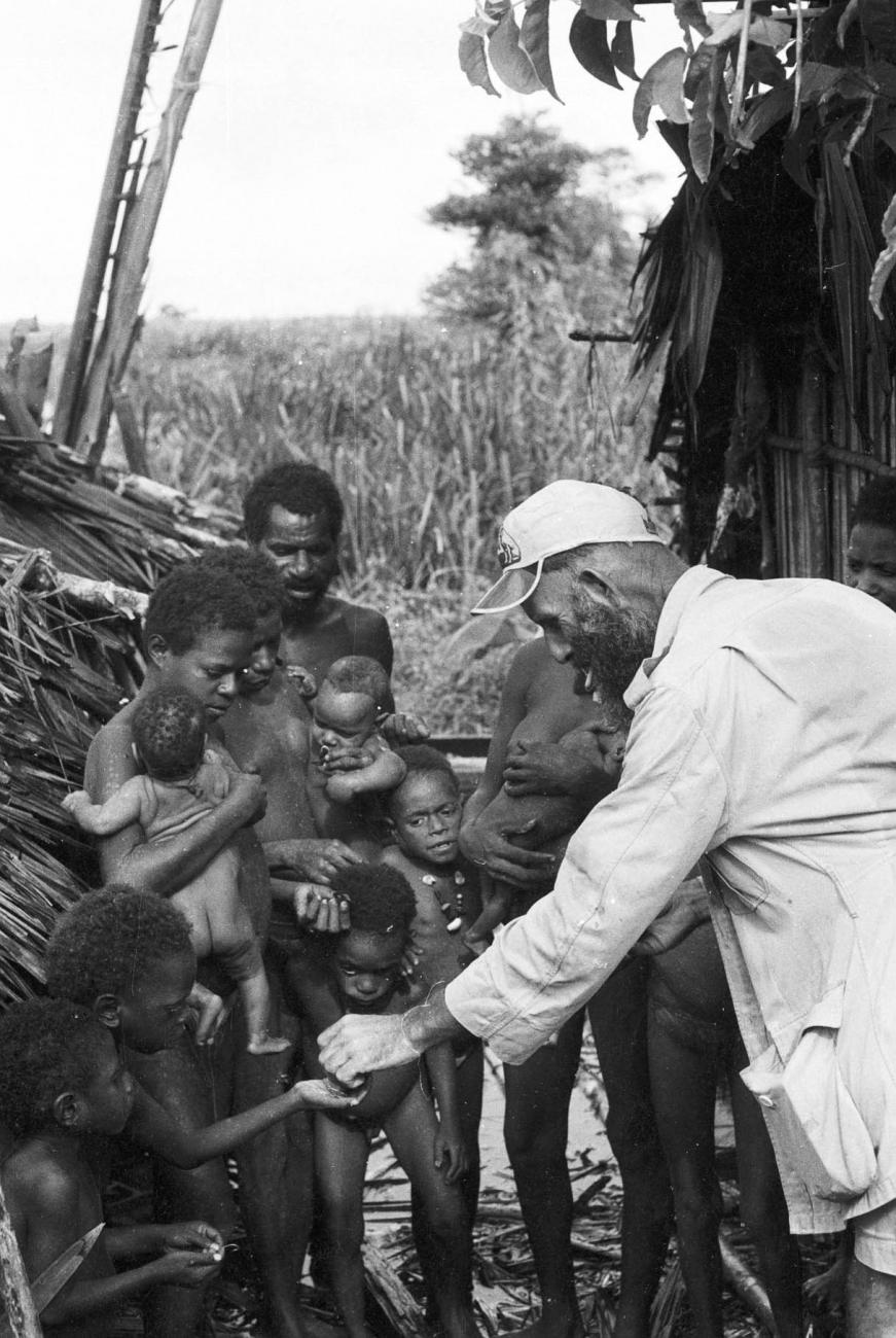 BD/133/296 - 
Tocht Merauke-Kepi-Cook: Een zendeling deelt iets uit aan kinderen
