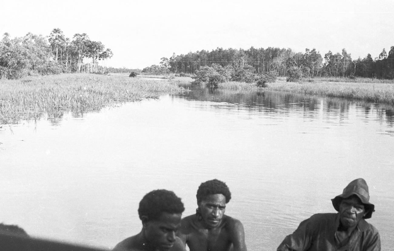 BD/133/322 - 
Tocht Merauke-Kepi-Cook: Uitzicht over het water en riet met Papoea&#039;s op de voorgrond
