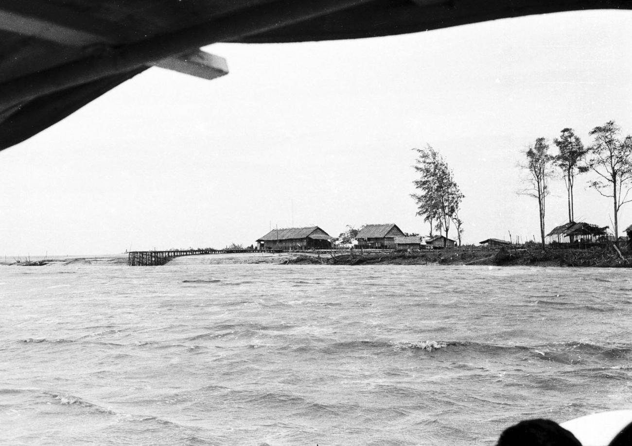 BD/133/324 - 
Tocht Merauke-Kepi-Cook: Uitzicht over het water op de nederzetting
