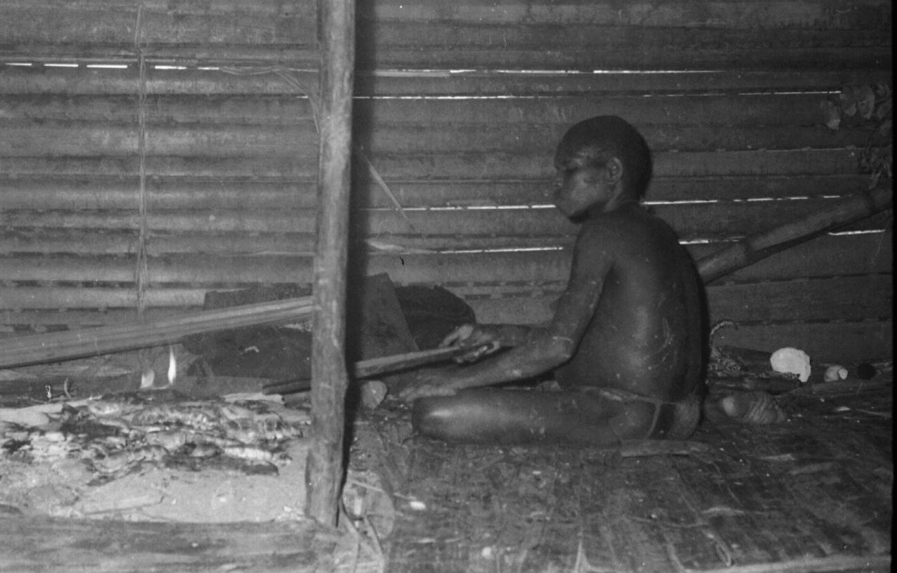 BD/133/62 - 
Tocht Merauke-Kapi: Marind-anim zittende bij de vuurplaats
