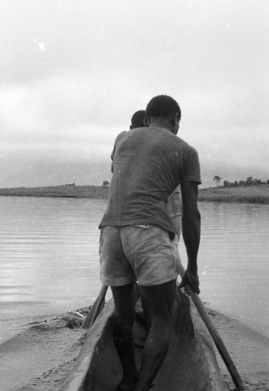 BD/133/643 - 
Twee Papoe-mannen staand met peddel voorin prauw
