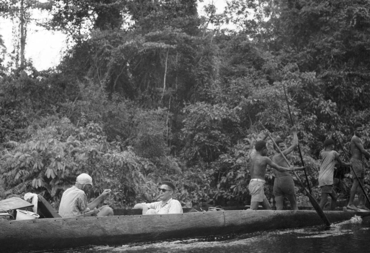 BD/133/663 - 
Prauw met Papoea&#039;s en een westerlingen, zij-aanzicht met hoge rivieroever als achtergrond
