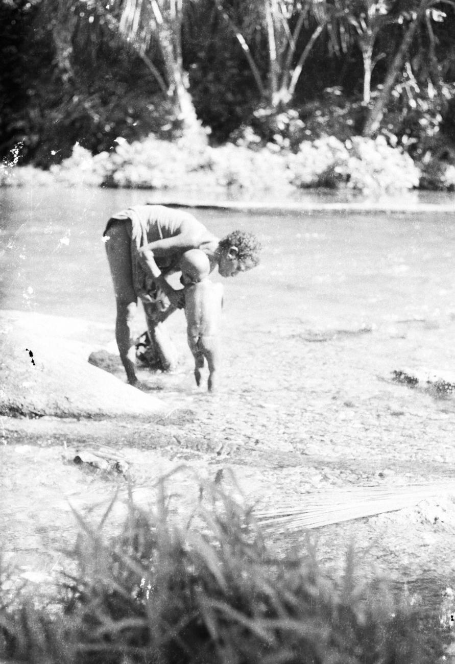 BD/133/691 - 
Papoea-vrouw wast haar kind op rivieroever
