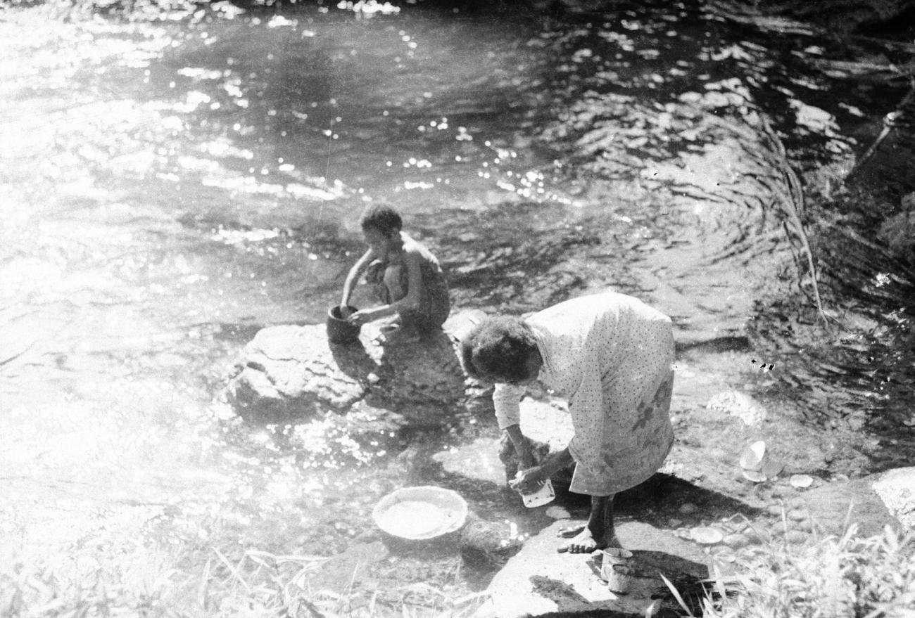 BD/133/692 - 
Papoea-vrouwen doen de vaat op de rivieroever
