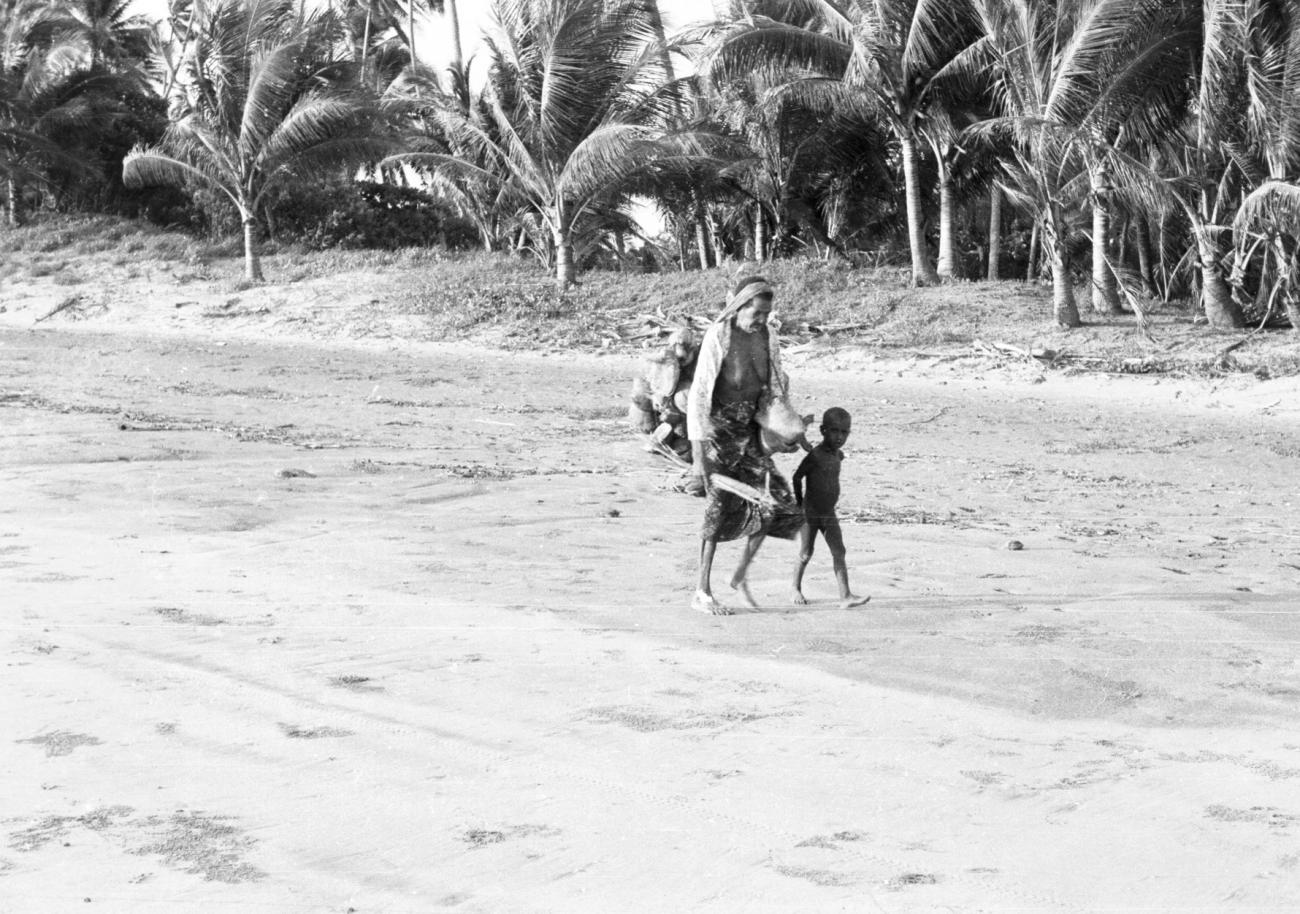 BD/133/830 - 
Paoea-vrouw en kind lopen over het strand
