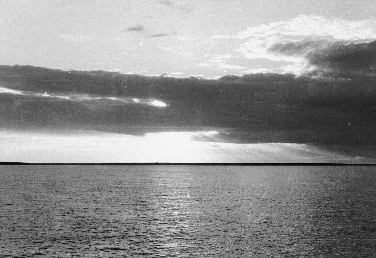 BD/133/856 - 
Kalme zee met kustlijn en donkere wolken
