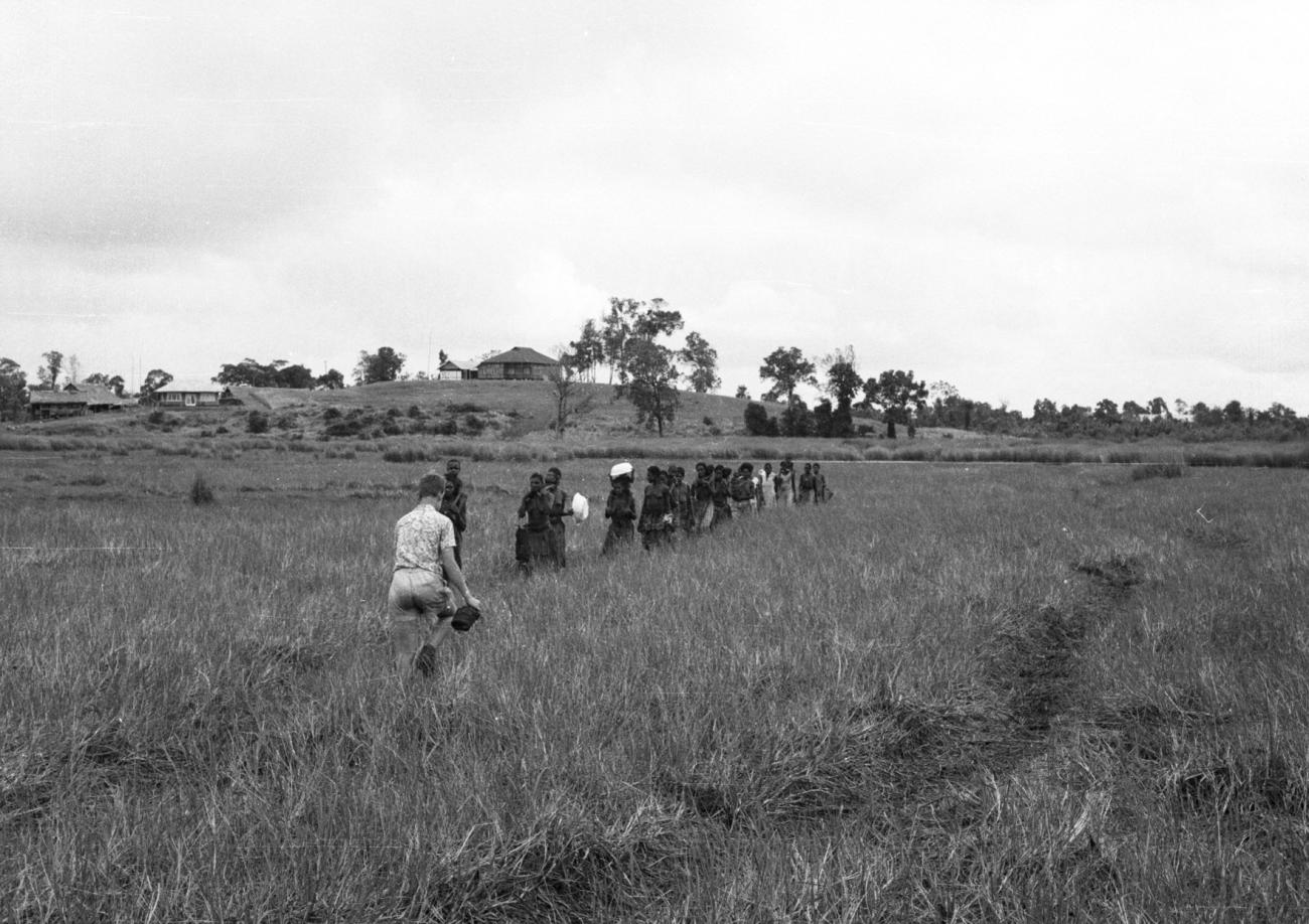 BD/133/875 - 
Groep Paoeavrouwen met kinderen op weg door het veld
