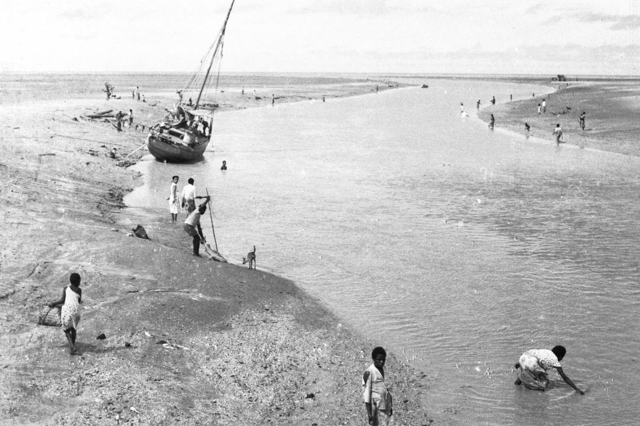 BD/133/946 - 
Getijdelandschap met met drooggevallen zeilschip en langs de oevers vissende Papoea&#039;s 
