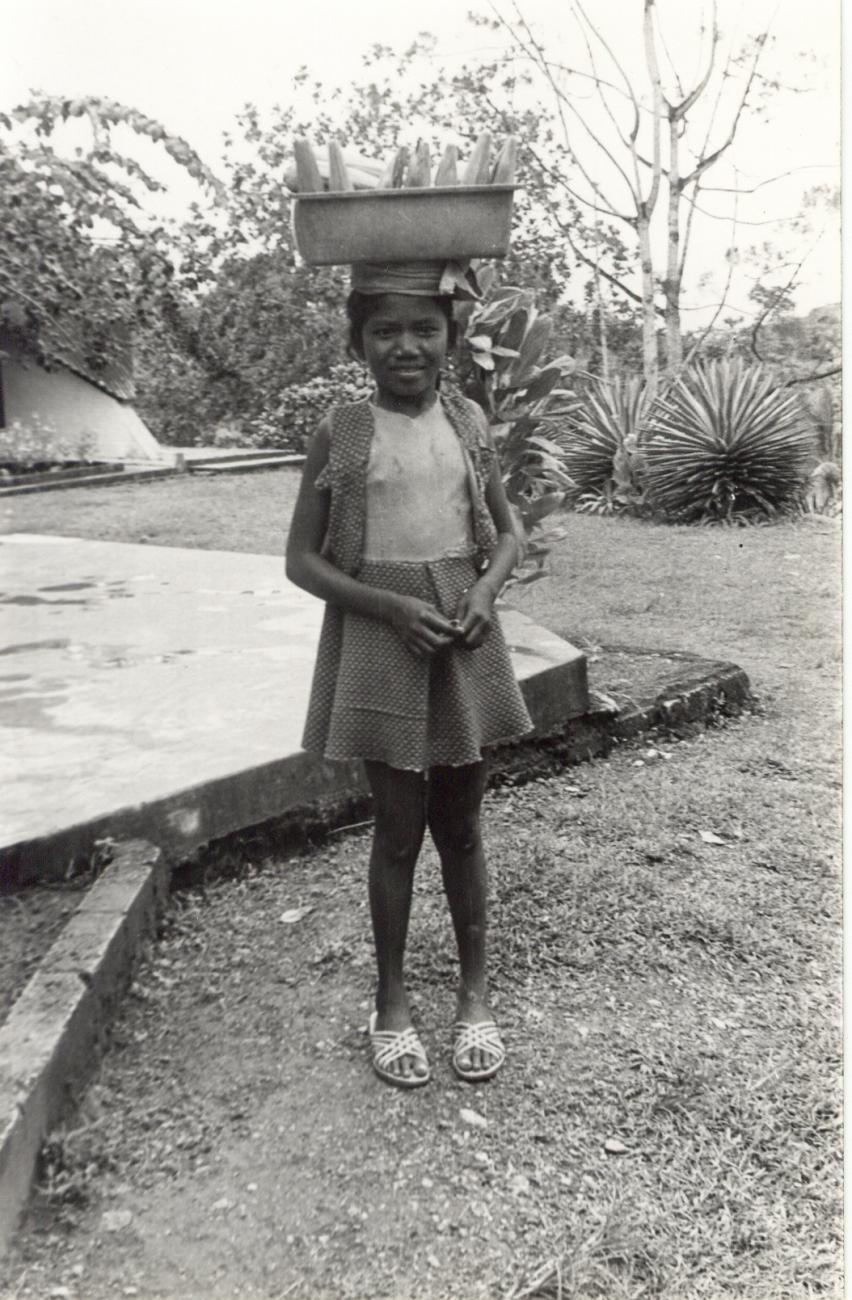 BD/253/10 - 
Portret van een kind met mand boven haar hoofd
