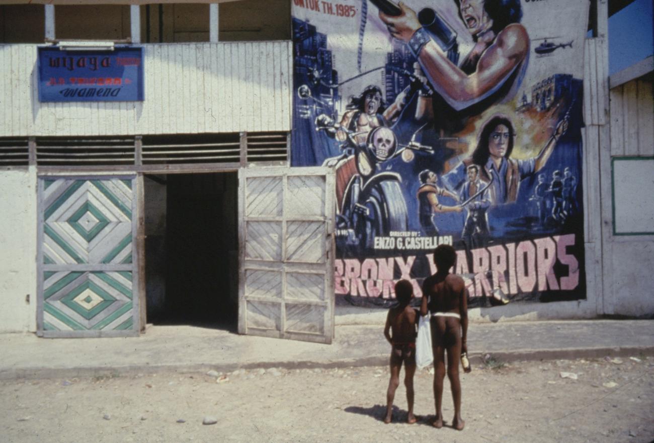 BD/285/79 - 
Twee Dani-jongetjes kijken naar een grote filmposter bij een bioscoop in Wamena
