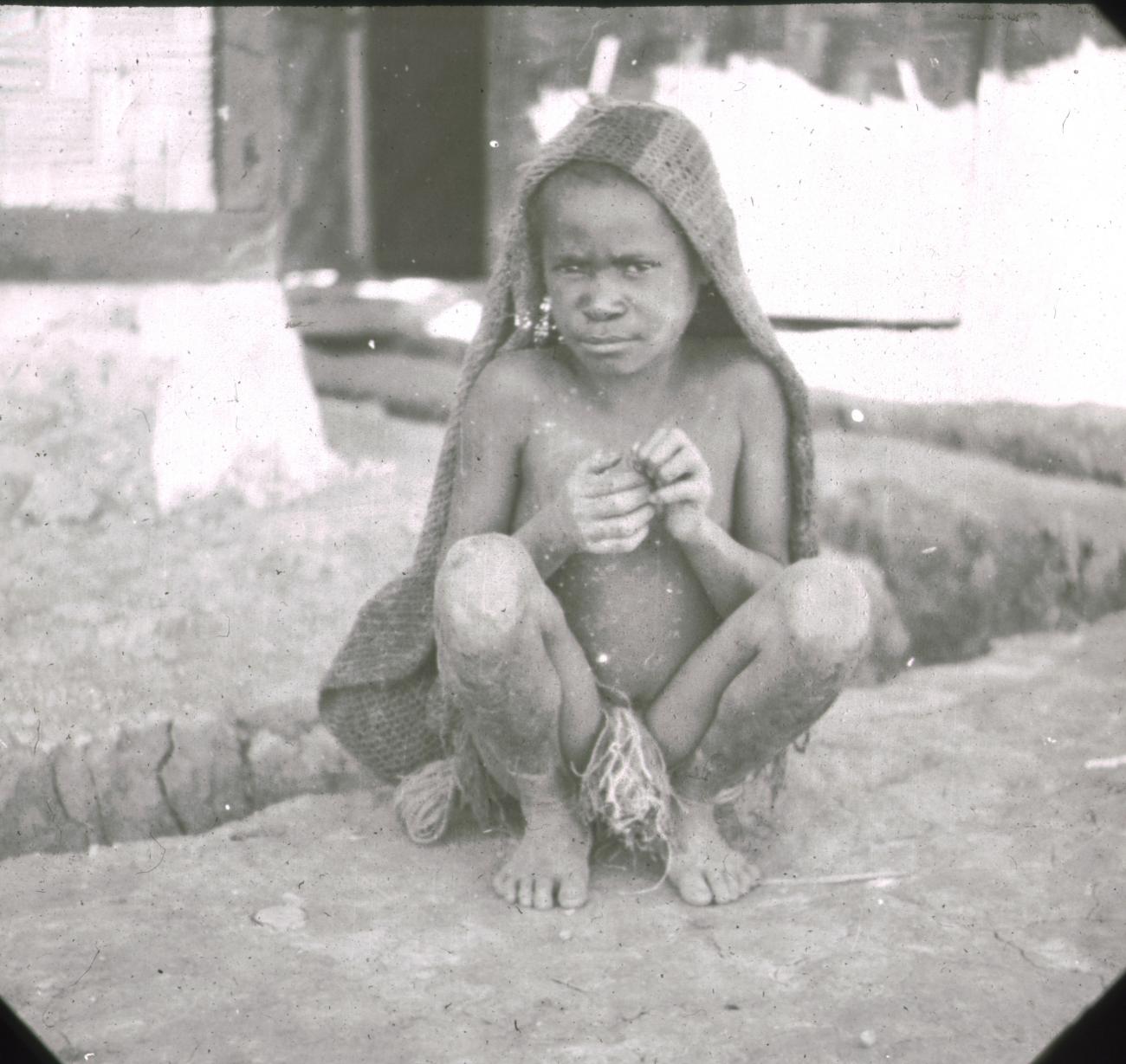 BD/329/11 - 
Papoea-kind in hurkhouding met doek of draagnet
