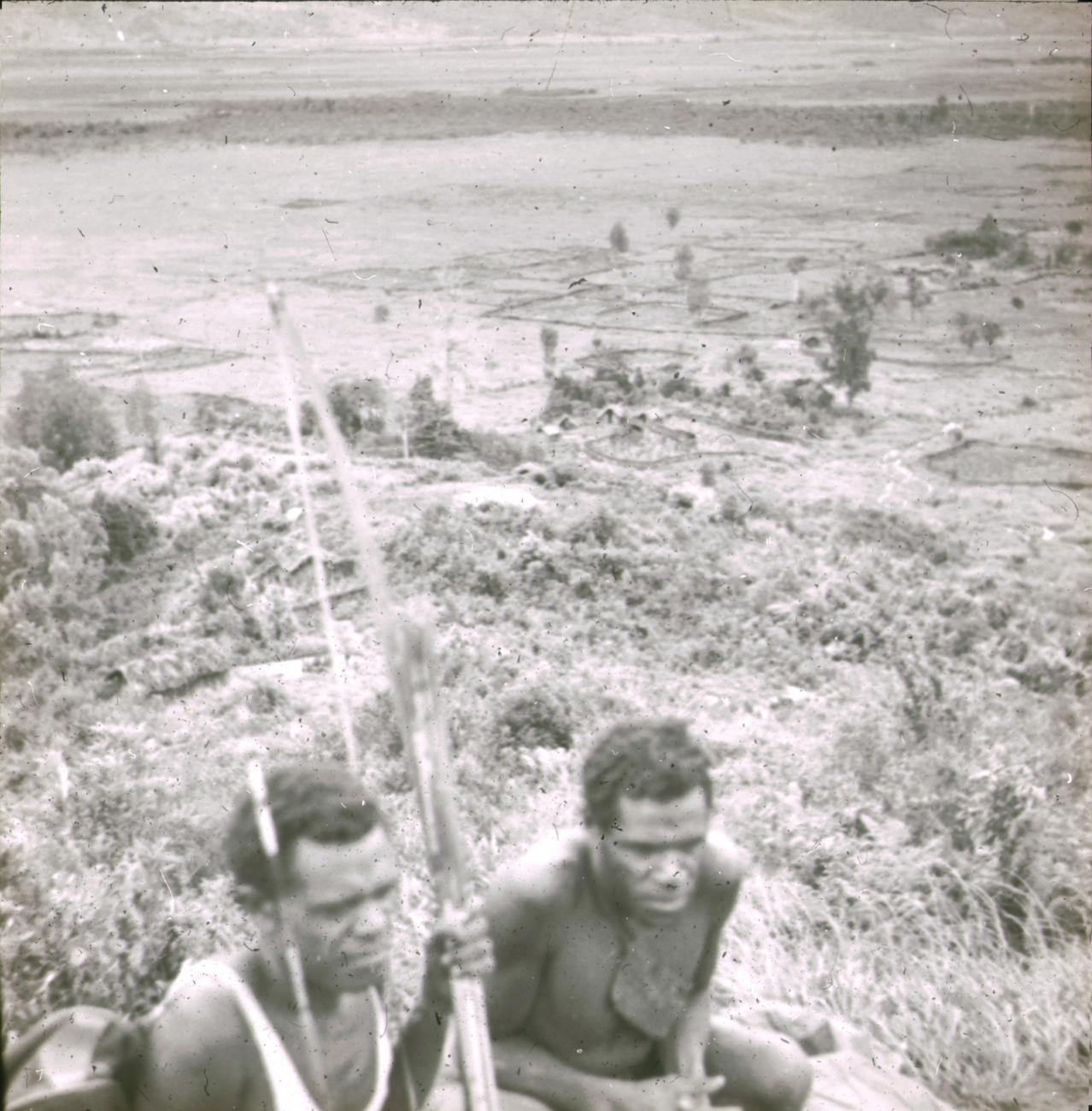 BD/329/32 - 
Zicht op vallei met cultuurgrond,  twee Papoea-mannen (
