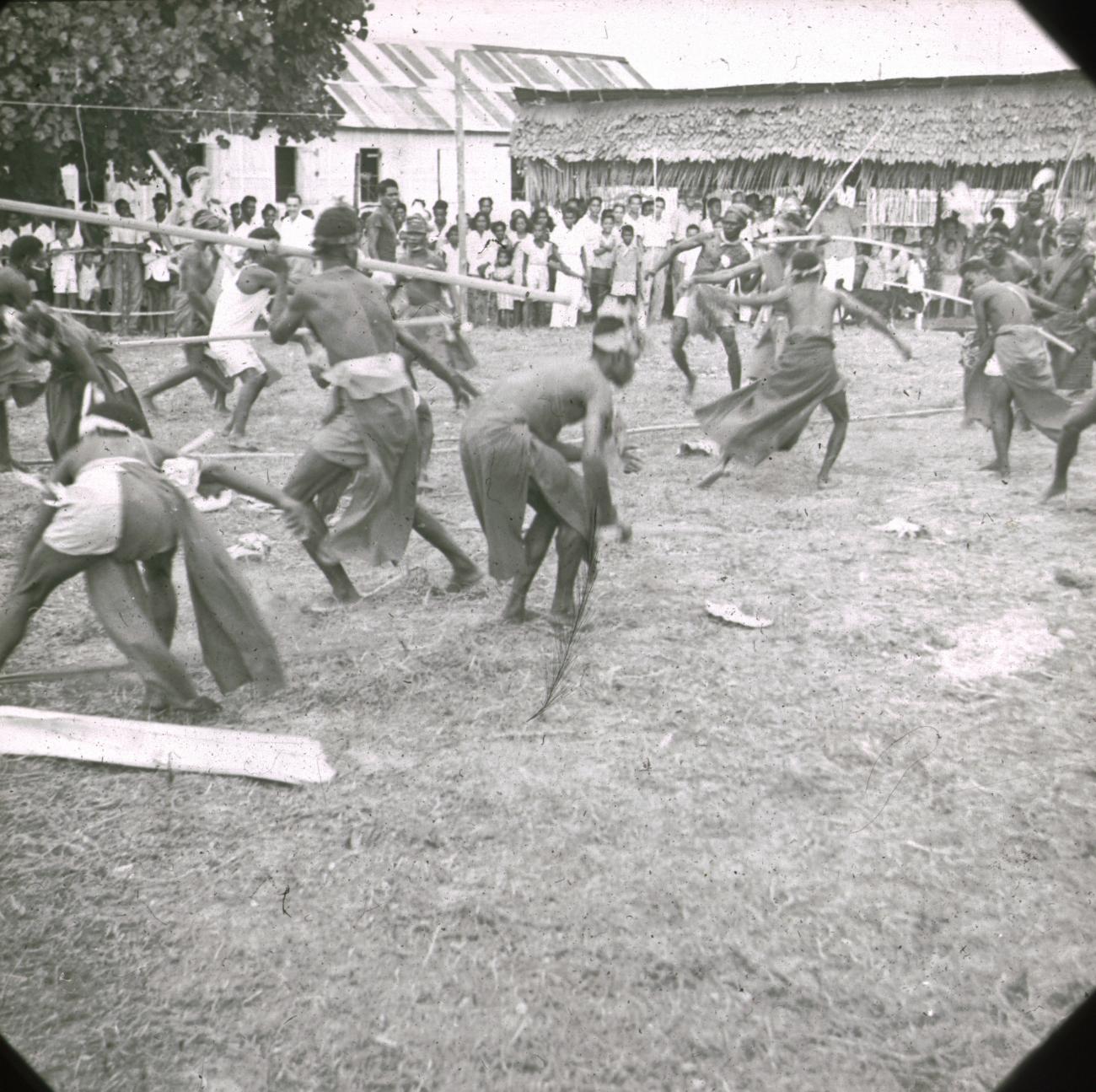 BD/329/41 - 
Papoea-mannen met omslagdoeken geven een opvoering (een soort gevechtsdans) voor een publiek
