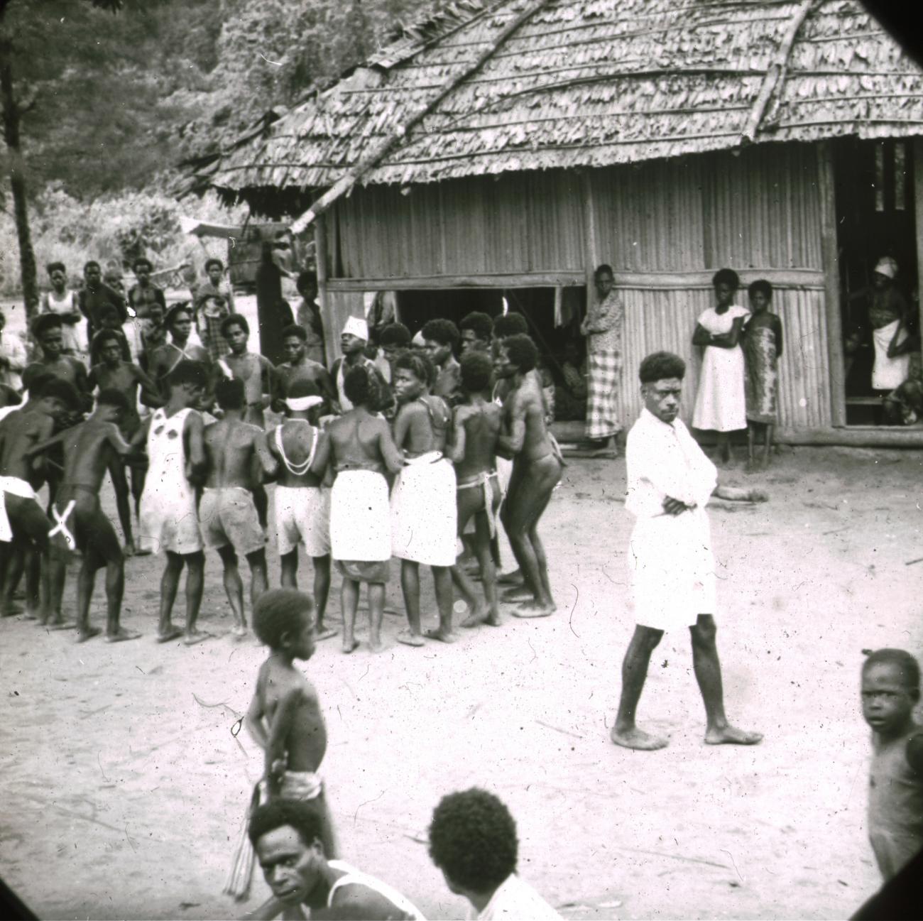 BD/329/42 - 
Groep Papoea-jongeren,deels westers gekleed, voert een soort dans uit
