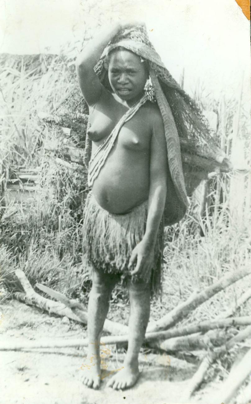 BD/40/48 - 
Vrouwelijke Papoea met rokje, en hoofdbedekking
