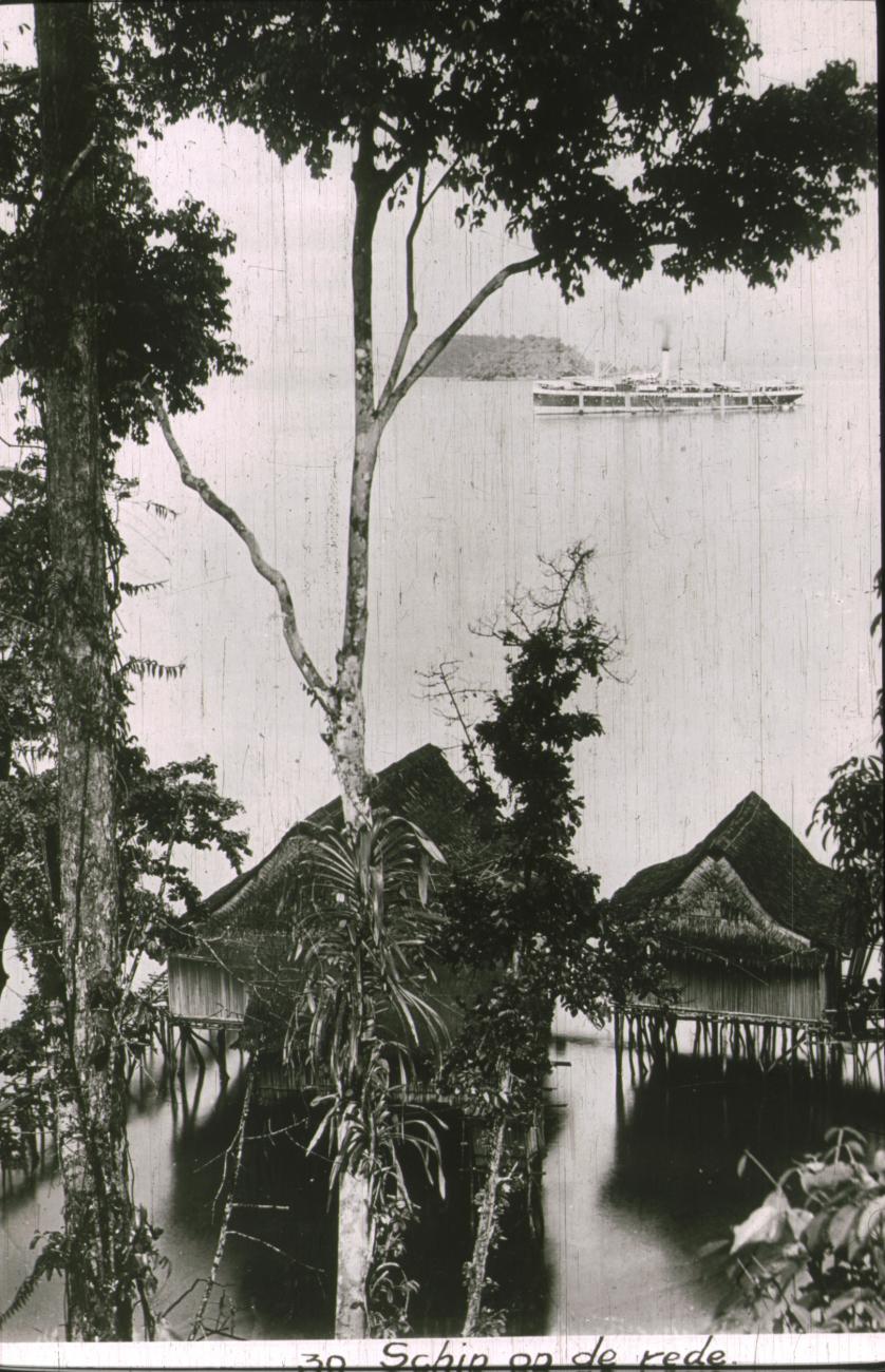 BD/186/104 - 
Schip op de rede met op de voorgrond paalwoningen
