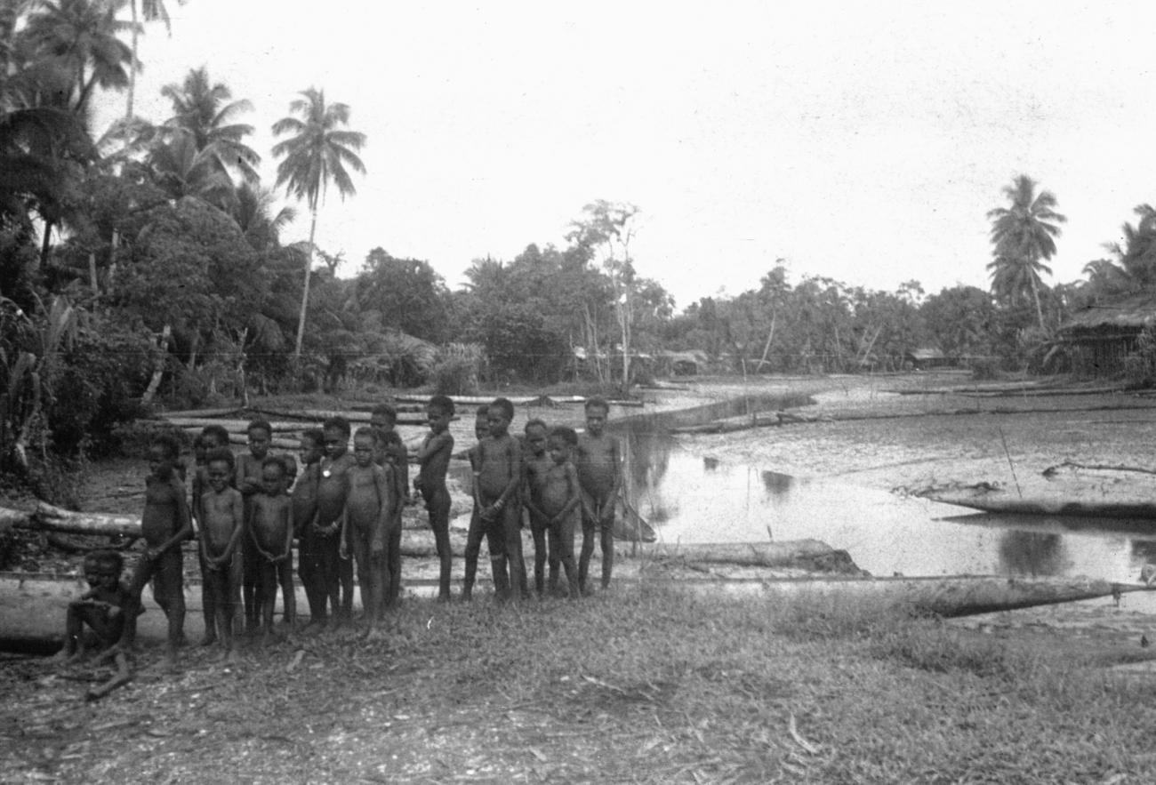 BD/216/105 - 
Groep Asmatkinderen aan de kant van de rivier
