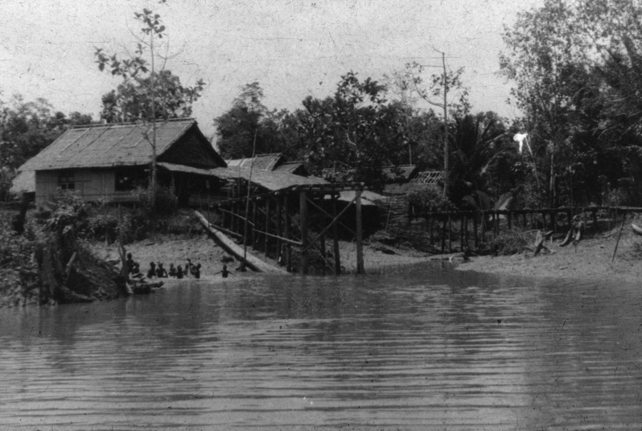 BD/216/16 - 
Huizen aan de oever van een rivier met spelende kinderen
