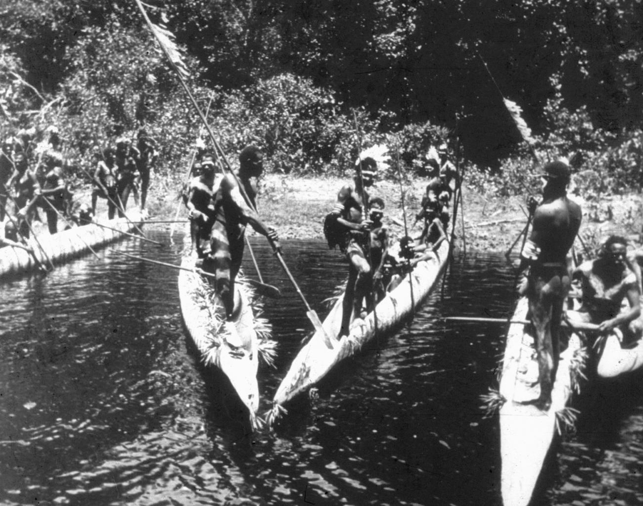 BD/216/178 - 
Feestelijk versierde Asmatters met prauwen op de rivier
