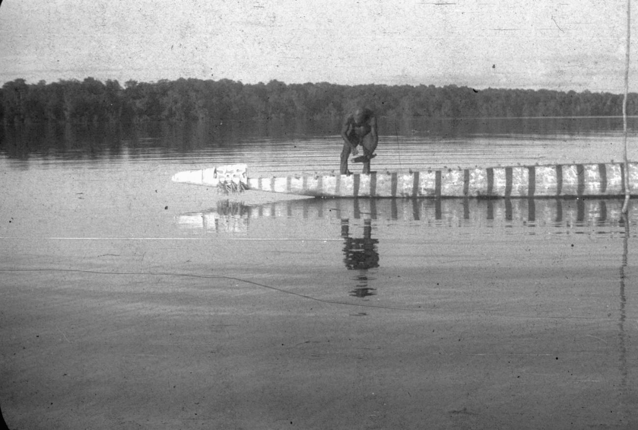 BD/216/189 - 
Asmatter staand in een nieuwe prauw in de rivier
