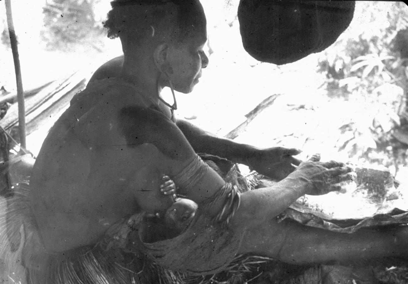 BD/216/242 - 
Vrouw aan het werk terwijl kind de borst krijgt

