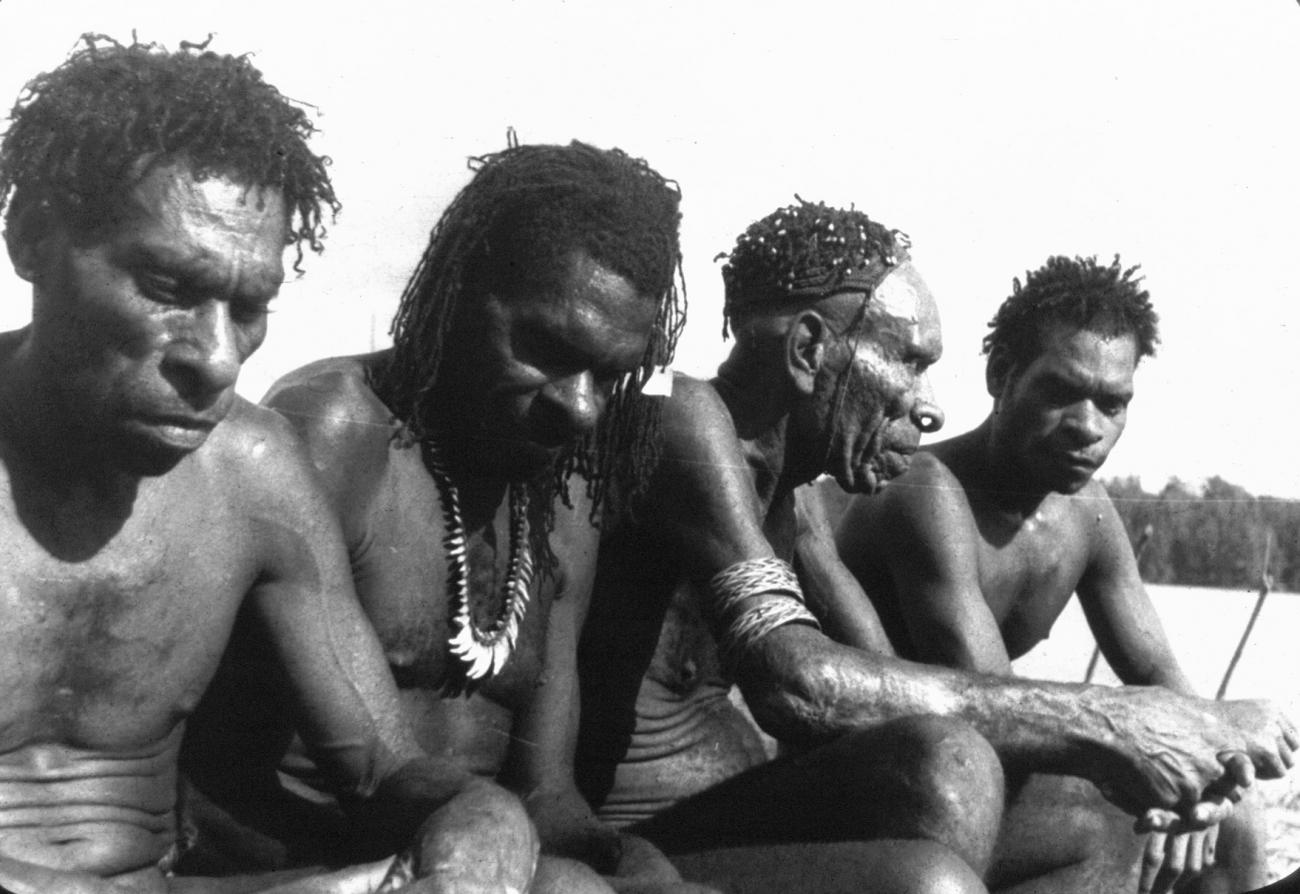 BD/216/86 - 
Vier mannen uit de Asmat aan rivier
