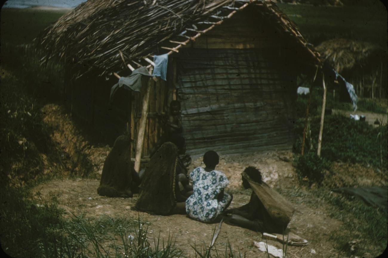 BD/248/252 - 
Berglandbewoners zittende voor een huis, van achteren gefotografeerd
