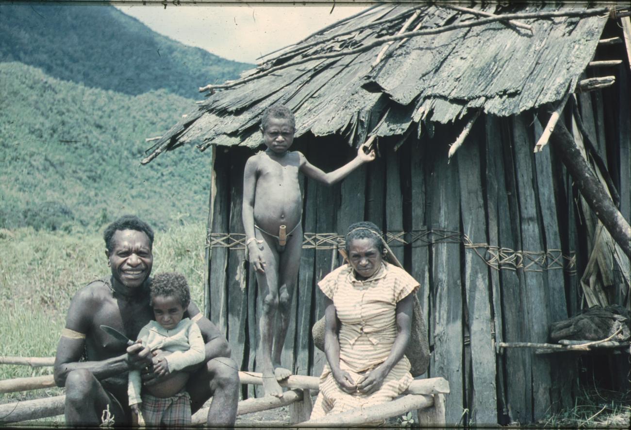 BD/248/8 - 
Man en vrouw met kinderen voor een hut
