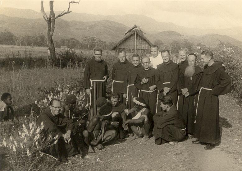 BD/269/23 - 
Franciscanen met Dani-mannen tijdens retraite in Wamena, Baliem-vallei, op de achtergrond een mannenhuis?

