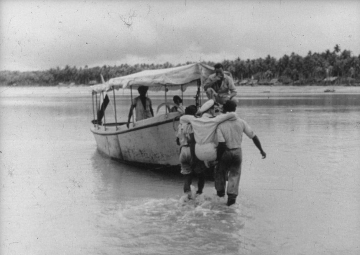 BD/285/131 - 
Militair wordt in motorboot geholpen door twee Papoea&#039;s
