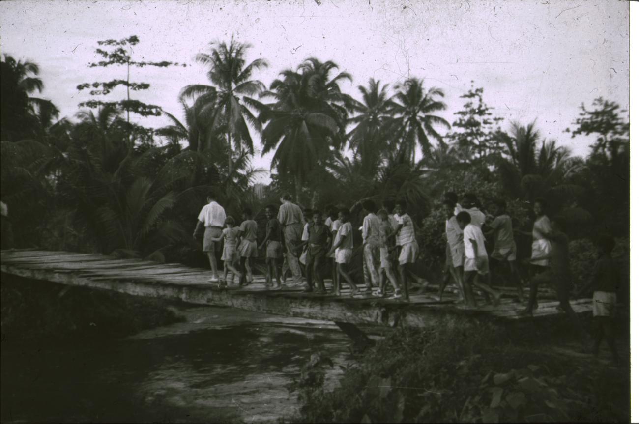 BD/309/235 - 
Leerlingen en leraren van de Jongens Vervolgschool JVVS op een brug over de rivier 
