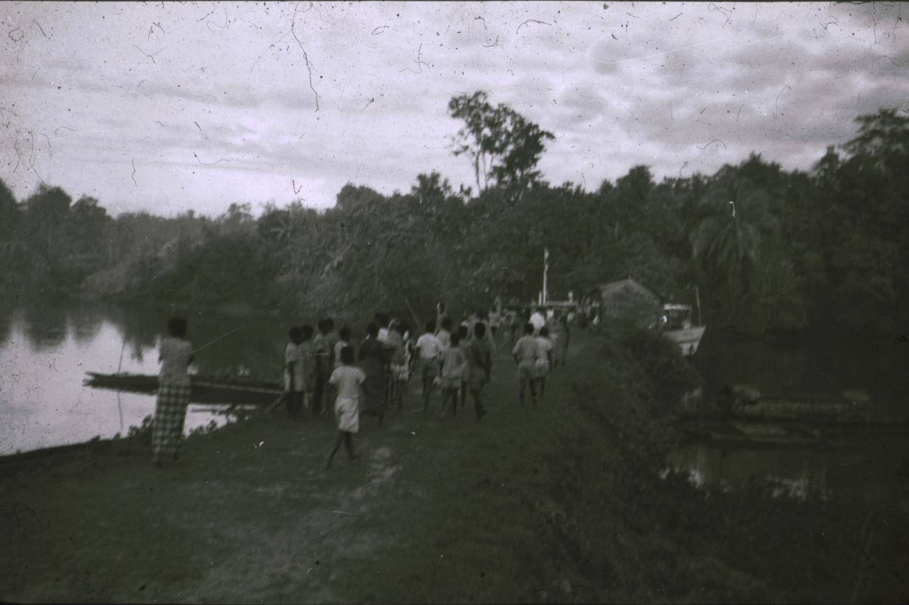 BD/309/237 - 
Groep leerlingen van de Jongens Vervolgschool JVVS in Teminabuan op weg naar de steiger met het gouvernementsvaartuig
