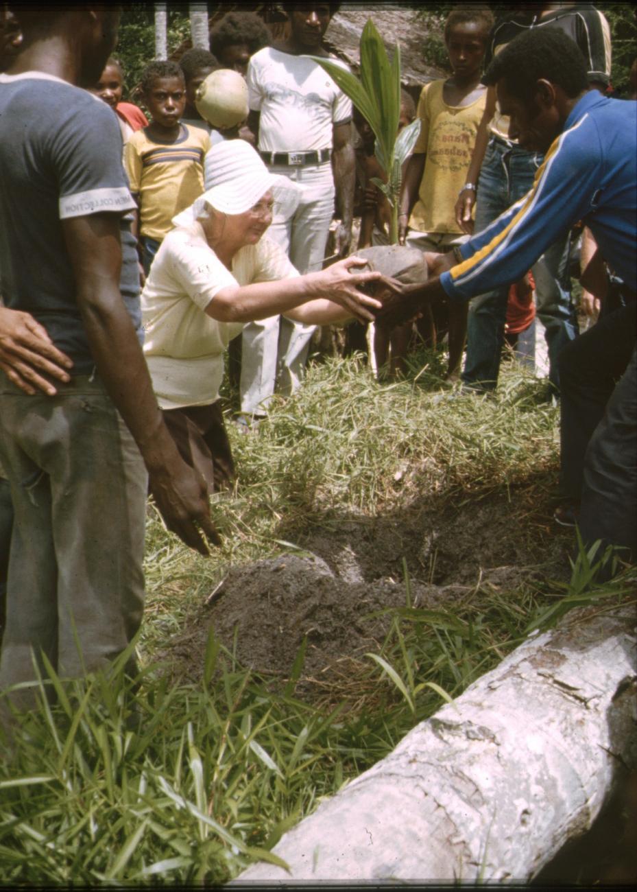 BD/309/338 - 
Mevrouw Marcus plant een nieuwe kokospalm in het dorp Konda
