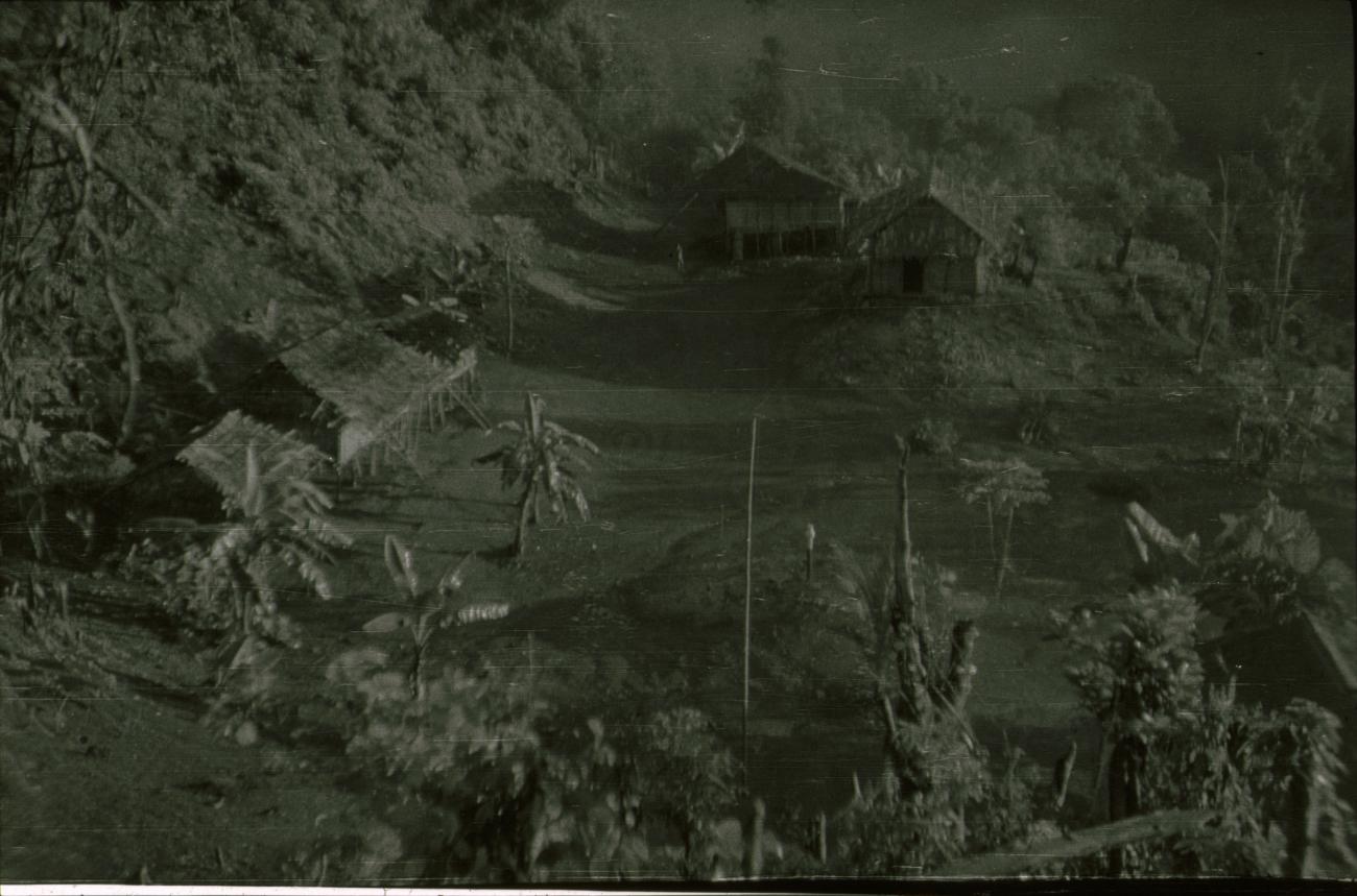 BD/309/385 - 
Dorpsgezicht met paalwoningen van het dorp Renis met in het midden een regenmeter
