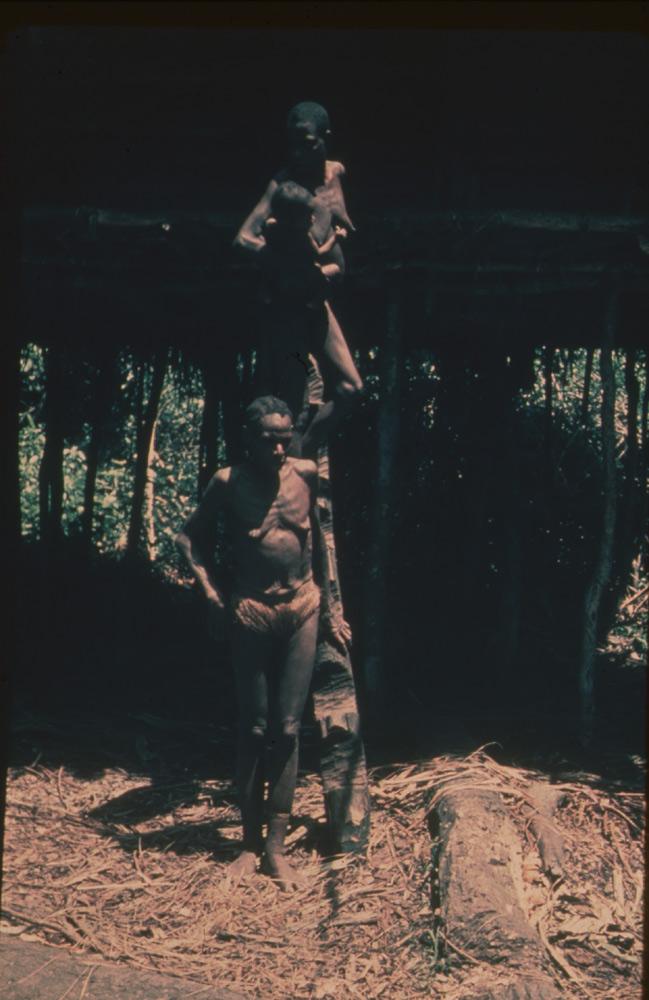BD/30/24 - 
Two women and a child leaving a stilt house by stairs
